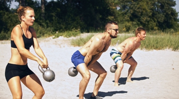 Outdoor fitness training with kettlebells on the beach