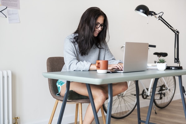 A woman sitting at a desk and typing on her laptop computer