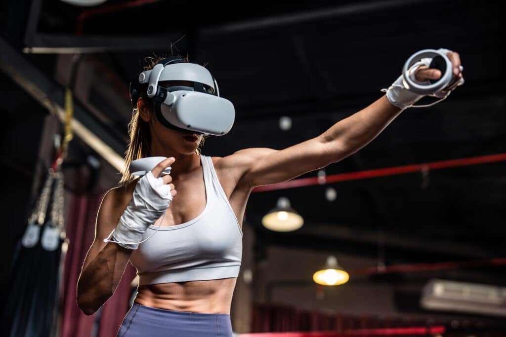 woman wearing virtual reality headset and hold gaming controller while doing boxing fight workout