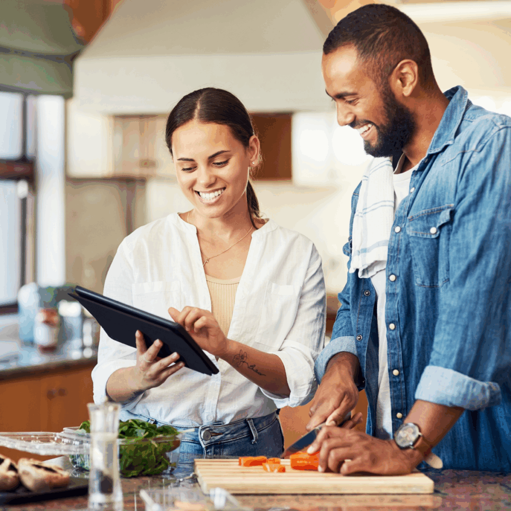 AFPA Certified Holistic Nutrition Coach Holding Tablet in Kitchen with Client While Preparing Food