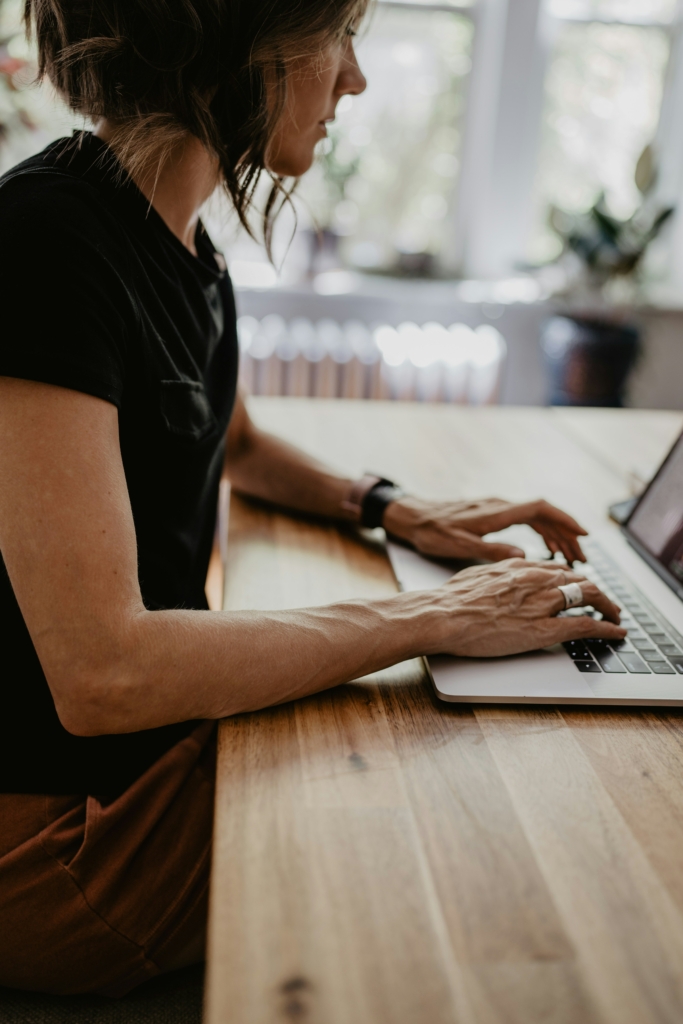 Woman studying for NBHWC exam on laptop